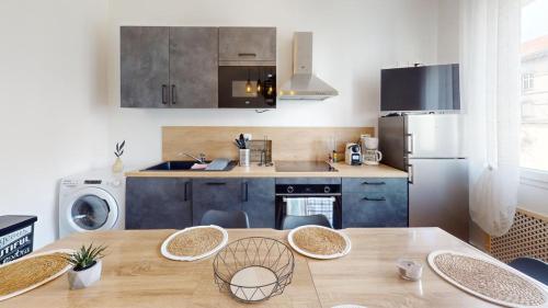 une cuisine avec une table avec des chaises et un réfrigérateur dans l'établissement Le Cour Vitton - Lyon 6ème - Proche Parc Tête d'Or, à Lyon