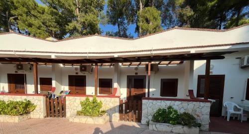 a white house with brown shutters and a patio at Villaggio Elisena in Vieste