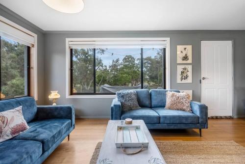 Una sala de estar con dos sofás azules y una mesa. en Peaceful Beachside Home, en Sandford