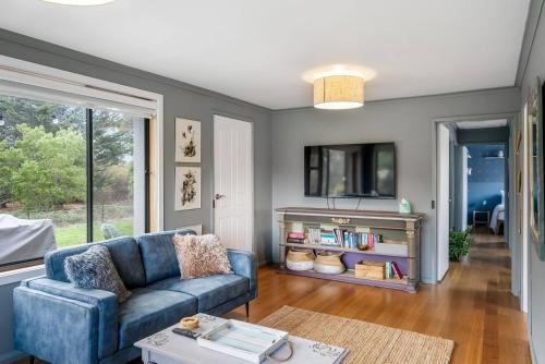 Una sala de estar con un sofá azul y un televisor. en Peaceful Beachside Home, en Sandford