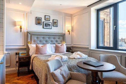a hotel room with a bed and a table and chairs at RÌGH Residences - George Street in Edinburgh