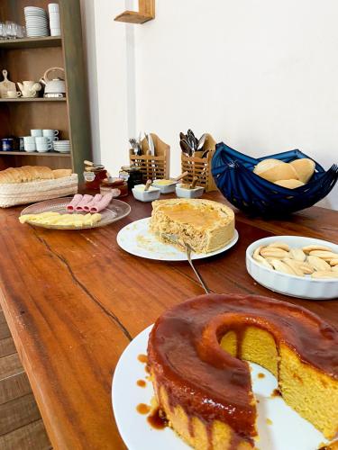 a wooden table topped with cakes and pies on plates at Pousada Oceano Atlântico in Marau