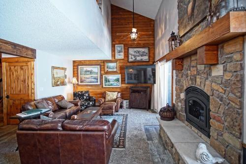 a living room with couches and a stone fireplace at Deck with Views, Gas Grill, Renovated Luxurious Townhome on Burgess Creek in Steamboat Springs