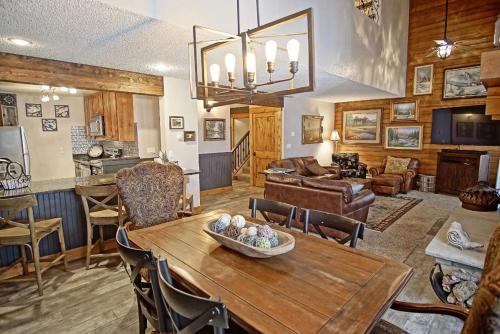 a living room with a wooden table and a kitchen at Deck with Views, Gas Grill, Renovated Luxurious Townhome on Burgess Creek in Steamboat Springs