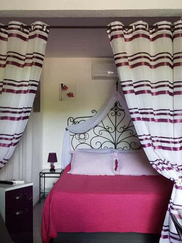 - une chambre avec un lit rose et des rideaux dans l'établissement Eolh, à Gréoux-les-Bains