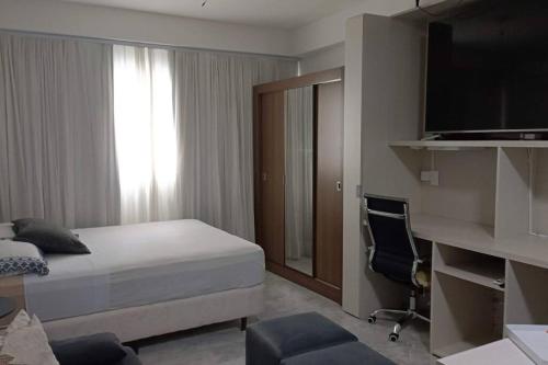 a bedroom with a bed and a desk and a television at Espaço especial IX in Curitiba
