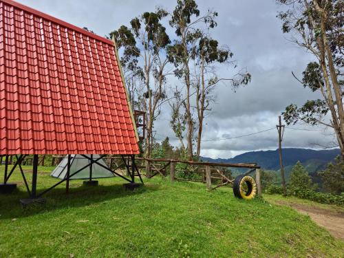 a red roofed building with a wheel on the grass at Wrongturnclub hilltop adventure stay in Kūkkāl