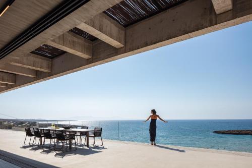 a woman standing on a balcony looking out at the ocean at Beach Rock in Chania Town
