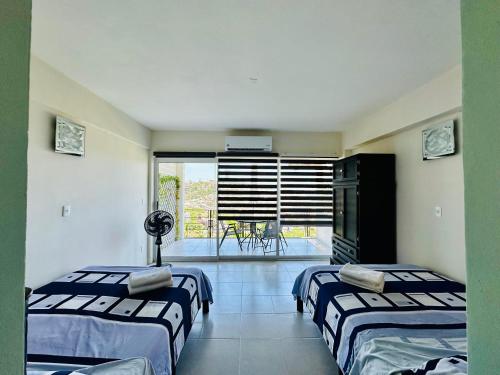 two beds in a room with a view of a balcony at Departamento La mejor vista de Acapulco en CasaBlanca Grand in Acapulco