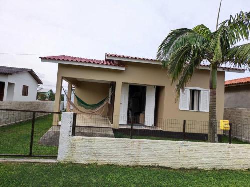 a house with a hammock in front of it at Casa na praia, 100 metros do mar in Arroio do Silva