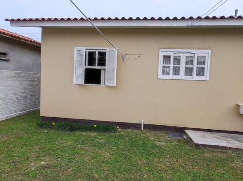 a white house with two windows and a yard at Casa na praia, 100 metros do mar in Arroio do Silva