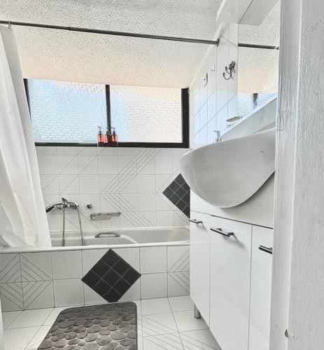 a white bathroom with a tub and a sink at Comfort and Sunny Apartment, Marousi OAKA Stadium Neratziotissa in Athens