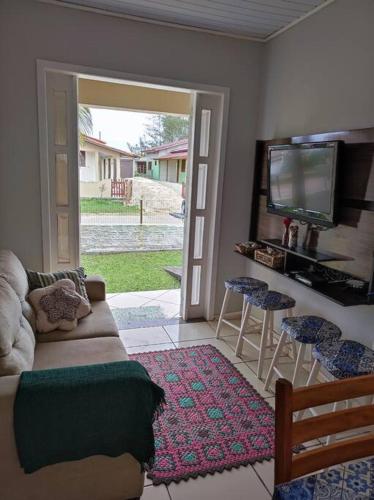 a living room with a couch and a tv at Casa na praia, 100 metros do mar in Arroio do Silva