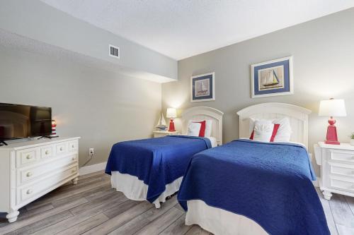 a bedroom with two beds with blue sheets and a tv at Anchorage 7473 in Hilton Head Island