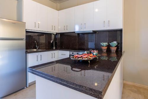 a kitchen with white cabinets and a bowl of fruit on a counter at Villy's Comfort Zone Apartments in Kalamata