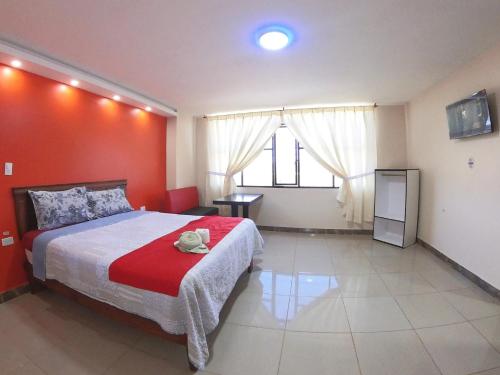 a bedroom with a large bed with a red wall at Hostal Flor de los Angeles Salcedo in San Miguel de Salcedo