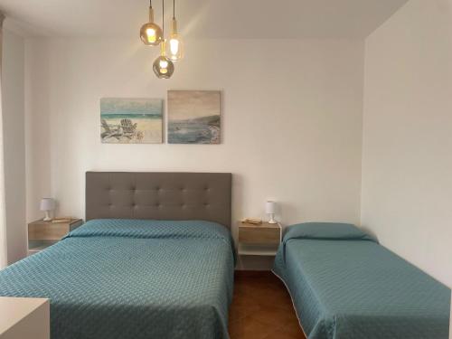 a bedroom with two beds and a chandelier at Kairos San Vito Lo Capo in San Vito lo Capo
