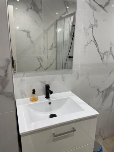 une salle de bain blanche avec un lavabo et un miroir dans l'établissement Beau studio proche mer, gare et commerces, à Antibes