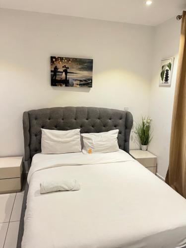 a bedroom with a large bed with white sheets at Embassy Gardens Royal Suites Apartments in Accra