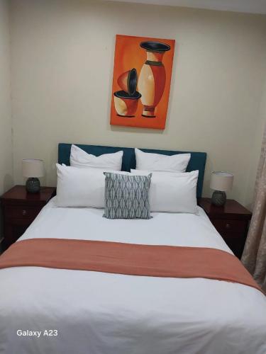 a bedroom with a white bed with a painting on the wall at CozyNest in Margate
