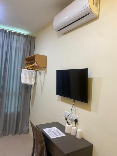 a room with a desk with a tv on the wall at Sunshine Hotel in Bahau