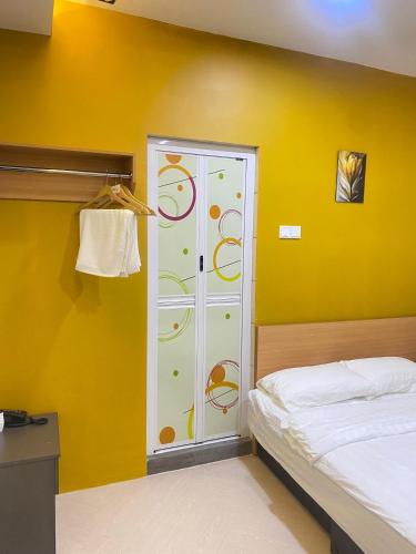 a bedroom with a bed and a yellow wall at Sunshine Hotel in Bahau
