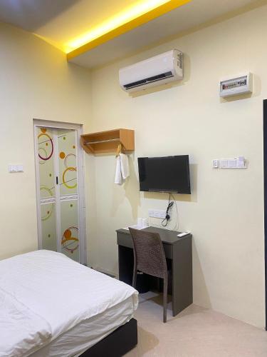a bedroom with a desk and a bed and a tv at Sunshine Hotel in Bahau