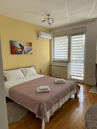 a bedroom with a large bed with two towels on it at Angellina Apartmani in Sremska Mitrovica