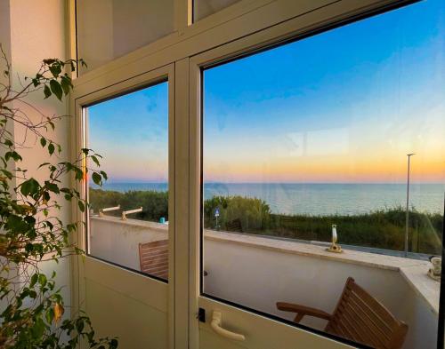 a door with a view of the ocean from a balcony at LA PERLA BIANCA Apartment - Near Train Station and Best Beaches with Amazing Sunsets in Anzio