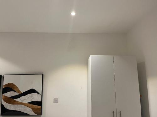 a white wall with a painting and a cabinet at Embassy Gardens Royal Suites Apartments in Accra
