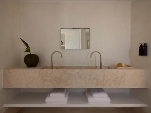 a bathroom with a large marble sink with two faucets at Akria Seaside Suites in Naousa