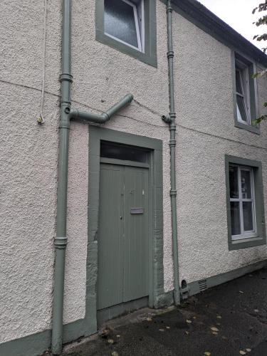 a white building with a green door and windows at Buccleuch and Queensberry Arms Hotel in Thornhill