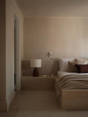 a white bedroom with a bed and a lamp at Akria Seaside Suites in Naousa