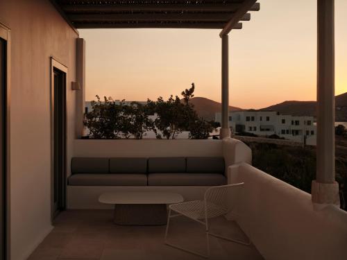 a couch on a balcony with a sunset in the background at Akria Seaside Suites in Naousa