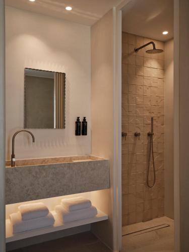 a bathroom with a tub and a shower with a sink at Akria Seaside Suites in Naousa