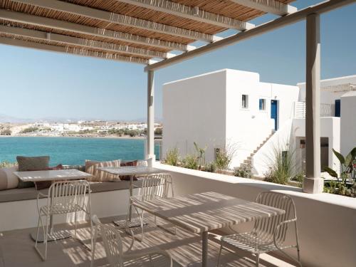 a balcony with tables and chairs and a view of the ocean at Akria Seaside Suites in Naousa