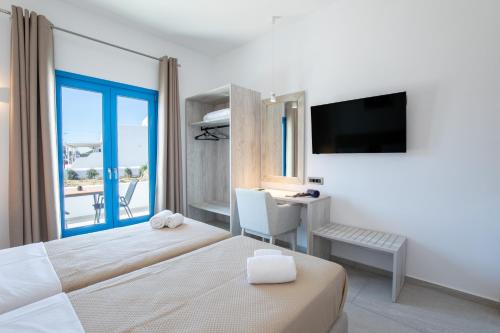 a hotel room with a bed and a desk and a television at Corfos Pearl Studios in Ornos