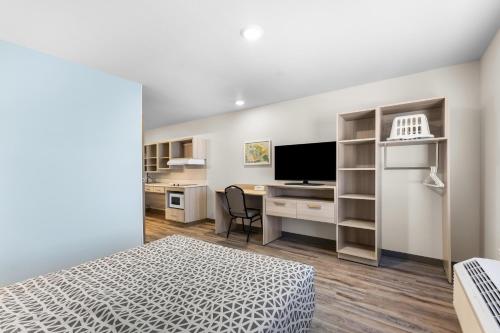 a bedroom with a bed and a desk with a television at WoodSpring Suites Bluffdale Salt Lake City in Bluffdale
