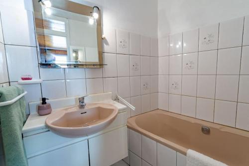 une salle de bain avec un lavabo, une baignoire et un miroir dans l'établissement La Rosée - 2 pièces familial, jardin privatif, à Bourbonne-les-Bains