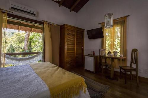 a bedroom with a bed and a desk and a window at Hotel Colinas de Petropolis in Petrópolis