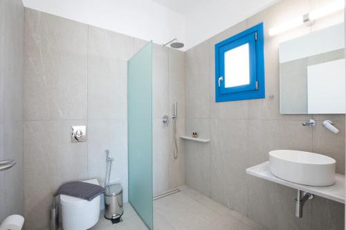 a bathroom with a sink and a toilet and a mirror at Corfos Pearl Studios in Ornos