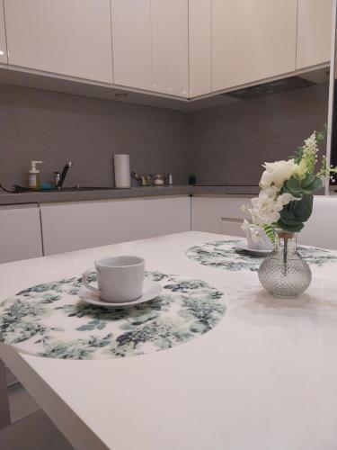 a coffee cup and a vase of flowers on a kitchen counter at Zlatarooms in Warsaw