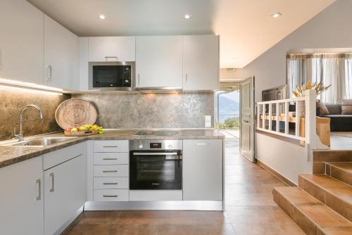 a kitchen with white cabinets and a sink at Braunis Horio Villas in Asos