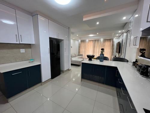 a kitchen with white counters and blue cabinets at Shobalenku Opulent apartments in Mbabane