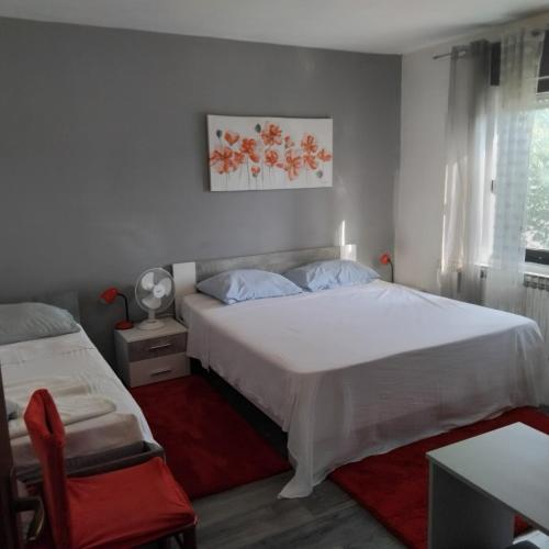 a bedroom with a white bed and a red chair at Dijana Gloria in Zadvorsko