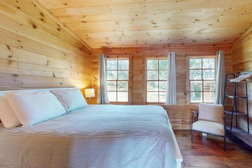a bedroom with wooden walls and a bed and a chair at Sunflower Cottage in Freeport