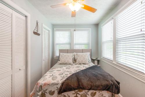 a bedroom with a bed with a ceiling fan and windows at Jacksonville Apartment with Private Patio Near NAS! in Jacksonville