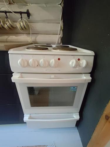 a white stove top oven in a kitchen at Viihtyisä mökki järven rannalla in Sysmä