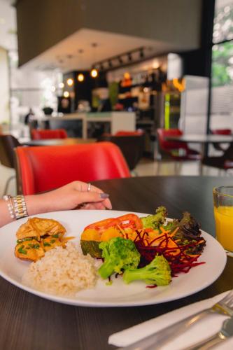 a woman sitting at a table with a plate of food at ibis budget BH Afonso Pena Savassi in Belo Horizonte