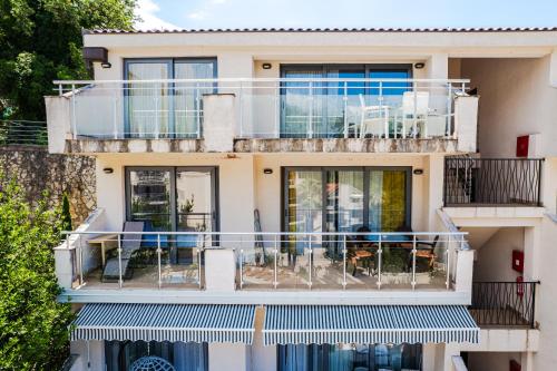 a building with a balcony with chairs and tables at Blue Horison Apartments by In Property in Pržno